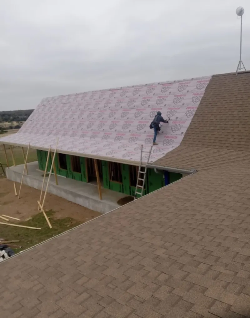 Worker preparing underlayment for a metal roof installation in Berlin